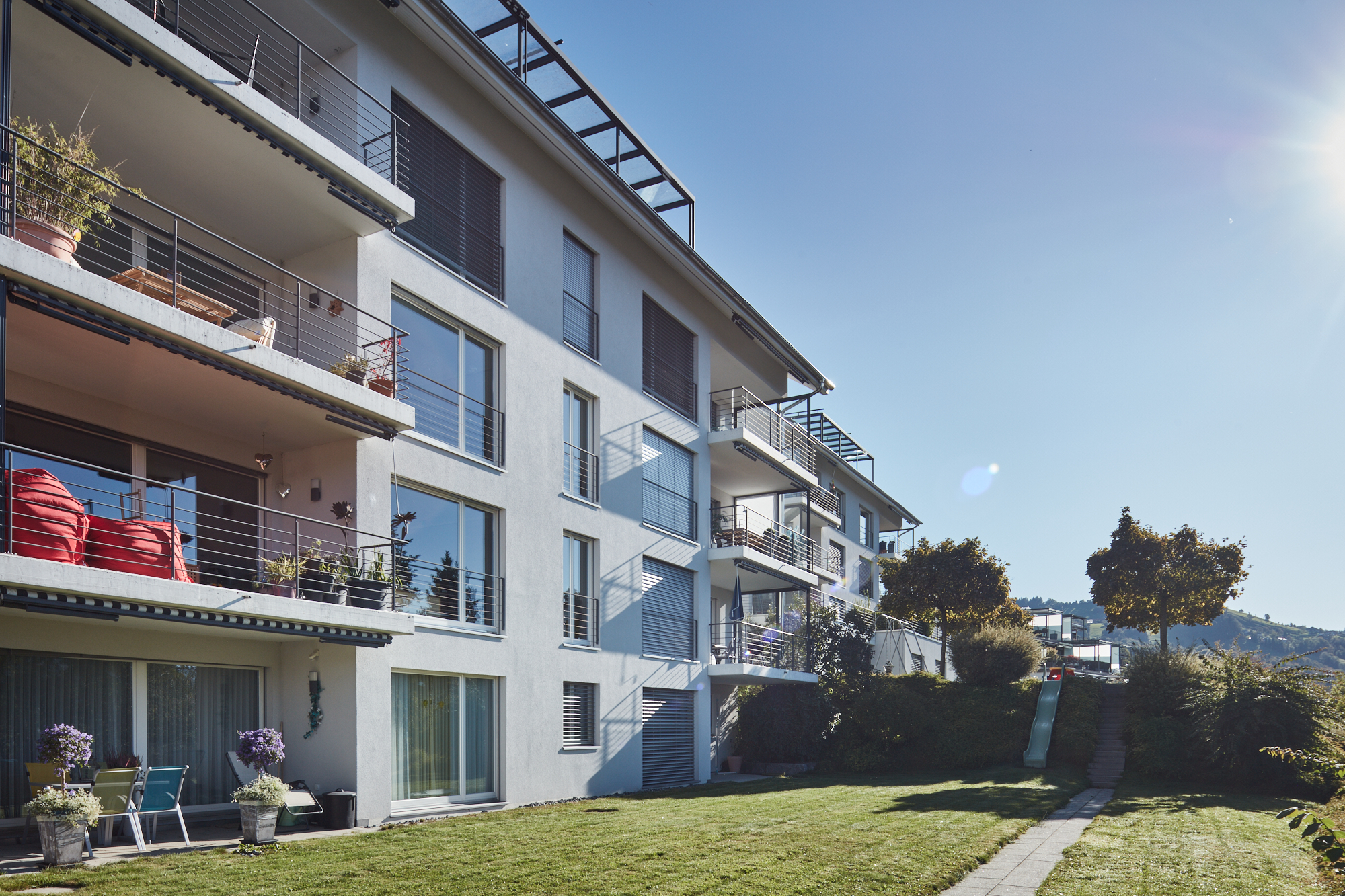 Mehrfamilienhaus mit Balkonen und Gartenanlage mit Rutsche