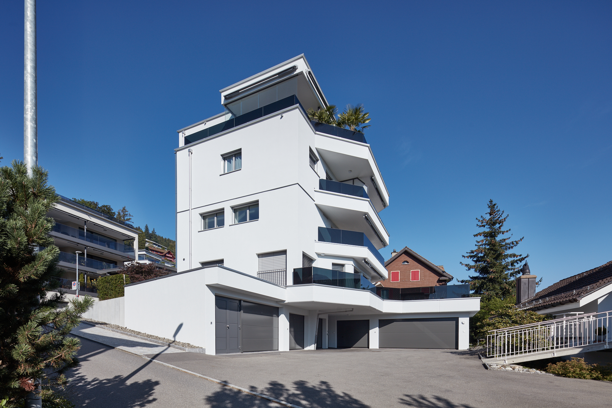 Weisses Terrassenhaus mit Garagen und Palmen auf dem Dach