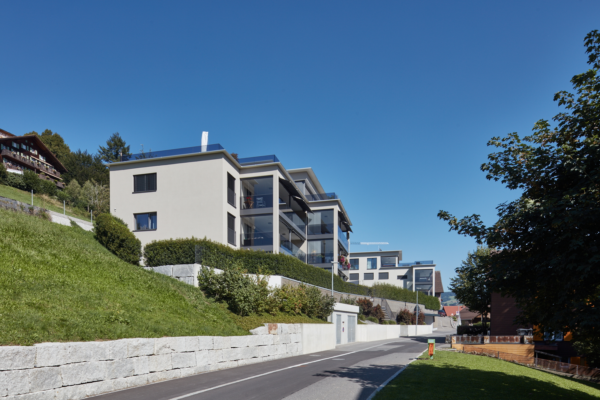 Wohnhäuser am Hang mit Granitmauer und verglasten Loggien